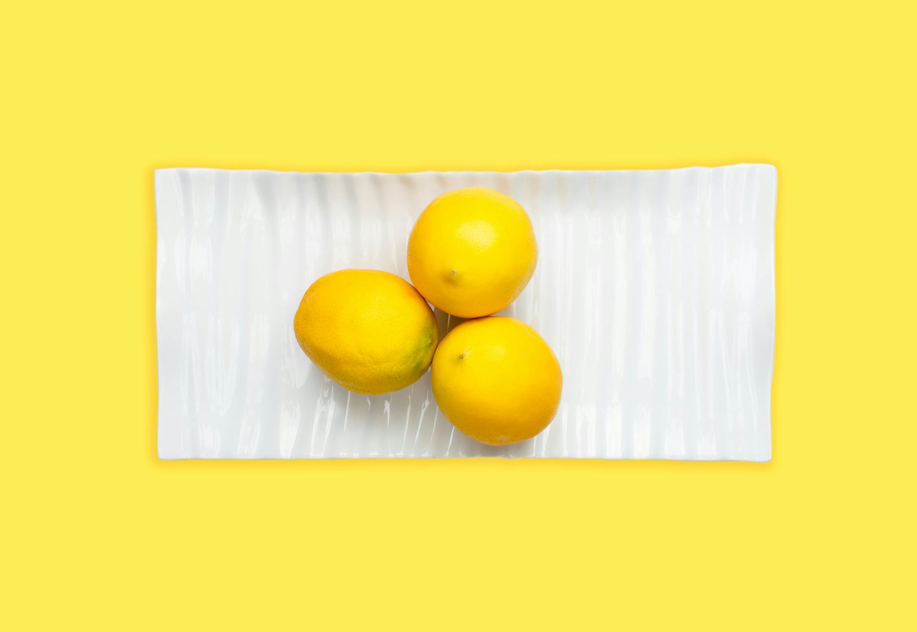 Bright yellow lemons on a soft pastel green background, symbolizing consistency and natural pleasure