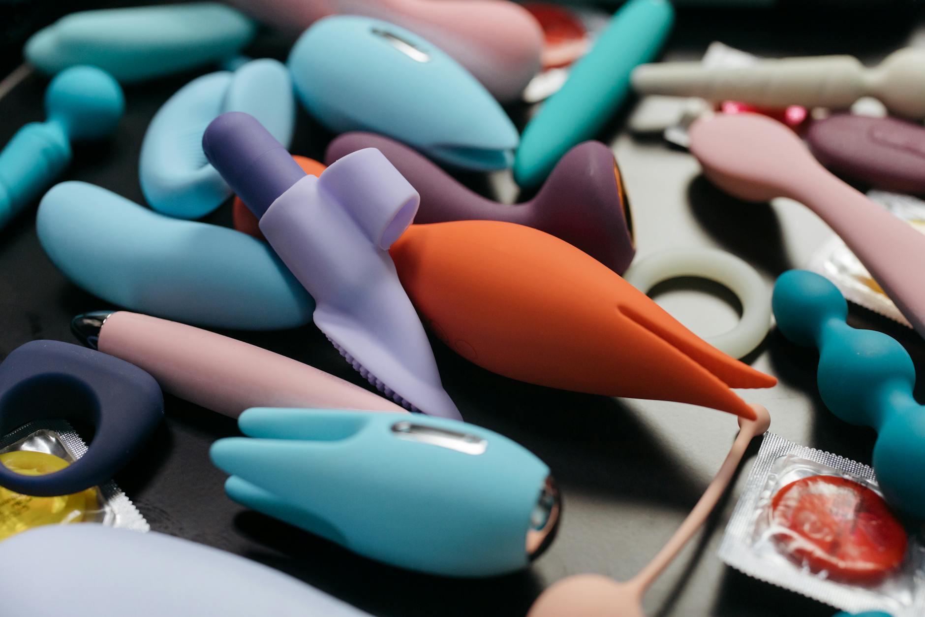 Hands holding a sleek blue vibrator against a purple background
