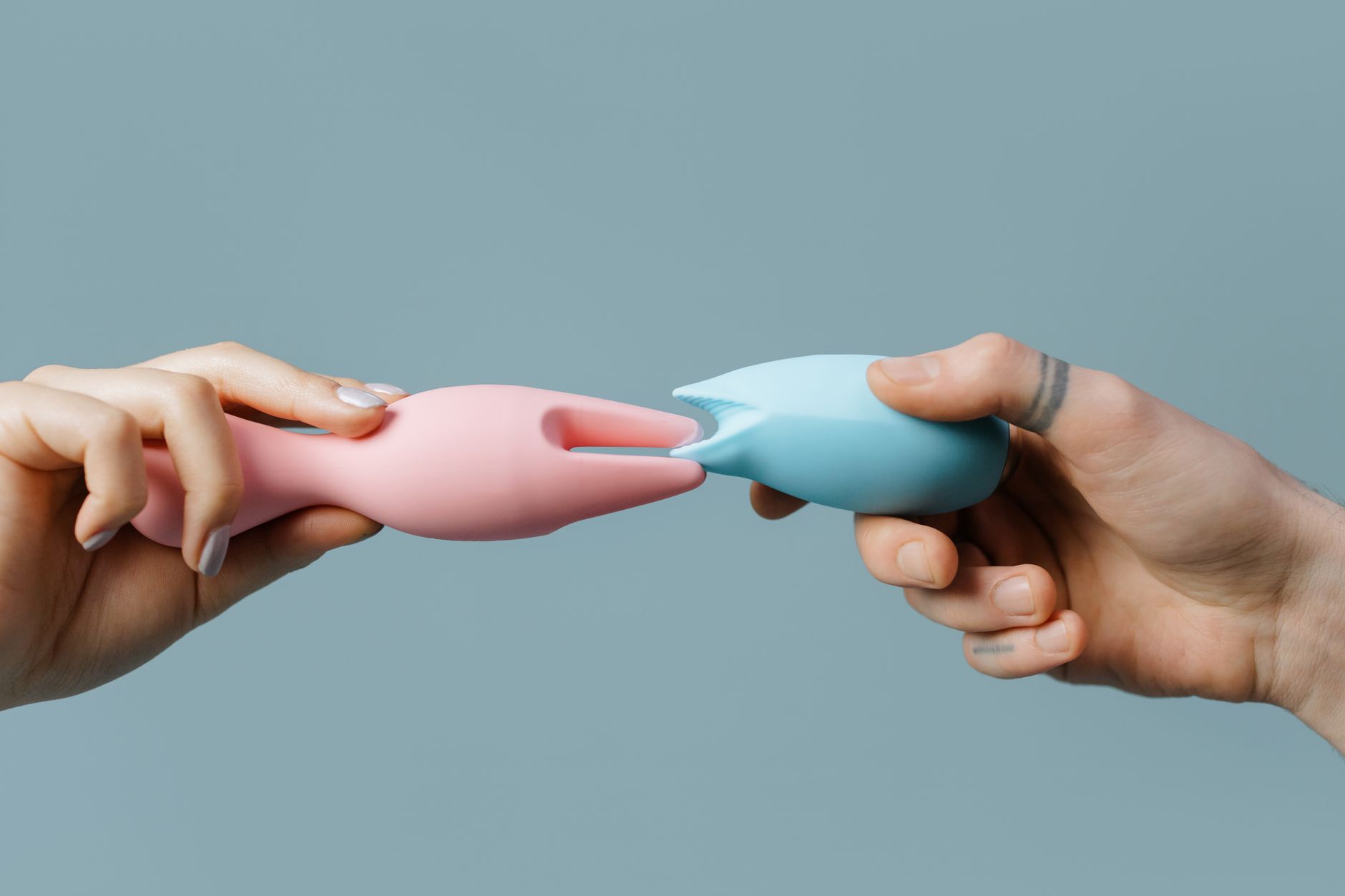 Close-up of hand holding an orange vibrator against a minimalistic purple backdrop, showcasing modern sensuality