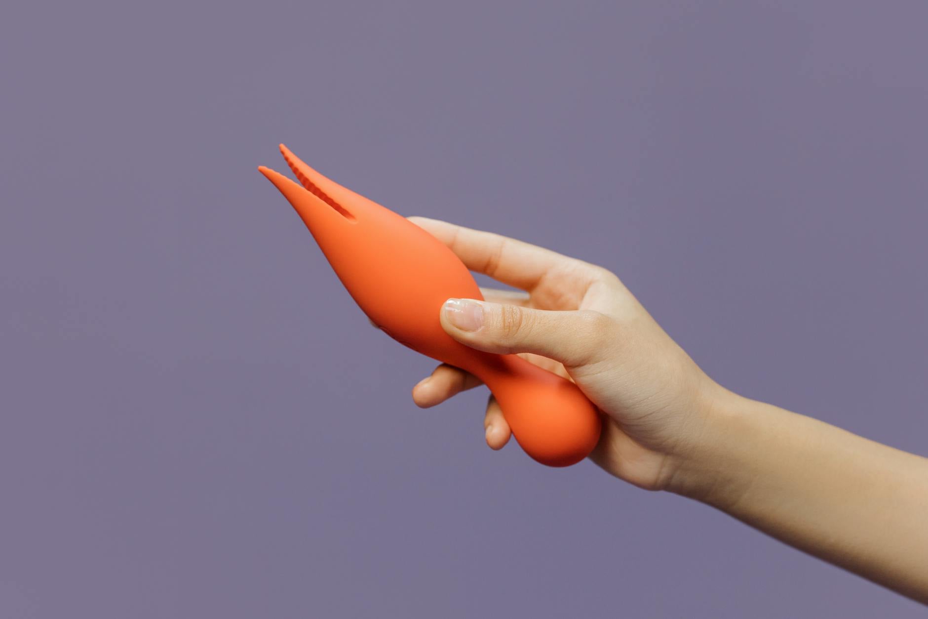 Hand holding a lemon vibrator against a minimalist purple background